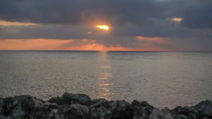 红色橙色的太阳升起在海面上，附近的岩石海岸，延时视频