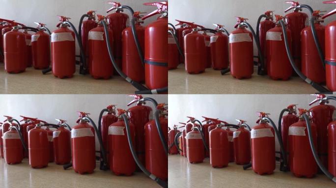 一堆过期的灭火器放在墙旁边的地板上。为企业更新灭火器。