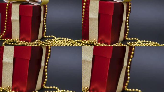 美丽的红色礼品盒，黑色背景上有金色蝴蝶结和珠子。