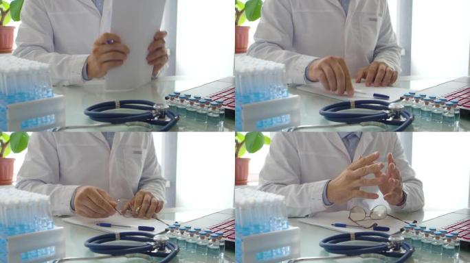 医生在笔记本电脑显示器前工作。他刷纸，放下笔，摘下眼镜。看来他有研究问题