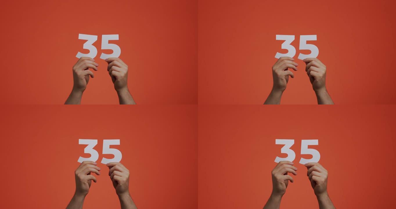 三十五号在手。显示数字的人，35个由雕刻纸制成的数字，用于投票或数学学习