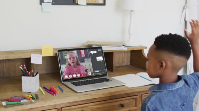 非裔美国男孩在家里用笔记本电脑进行视频通话时举手