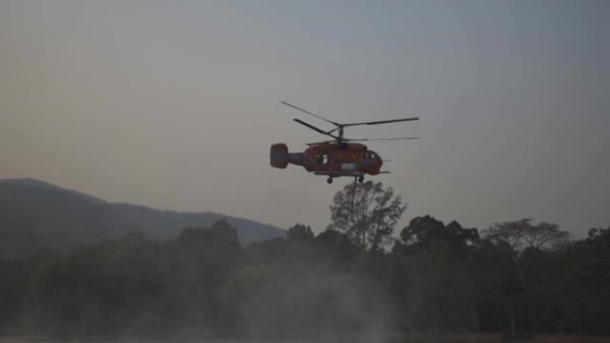 直升机和消防队员向野火森林的火场喷水