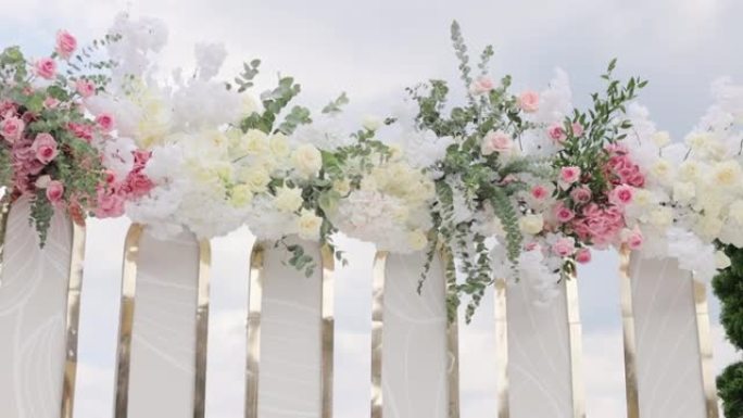 美丽的婚礼装饰。夏季阳光明媚的婚礼当天鲜花婚礼拱门。餐厅大厅里有鲜花的婚礼装饰品