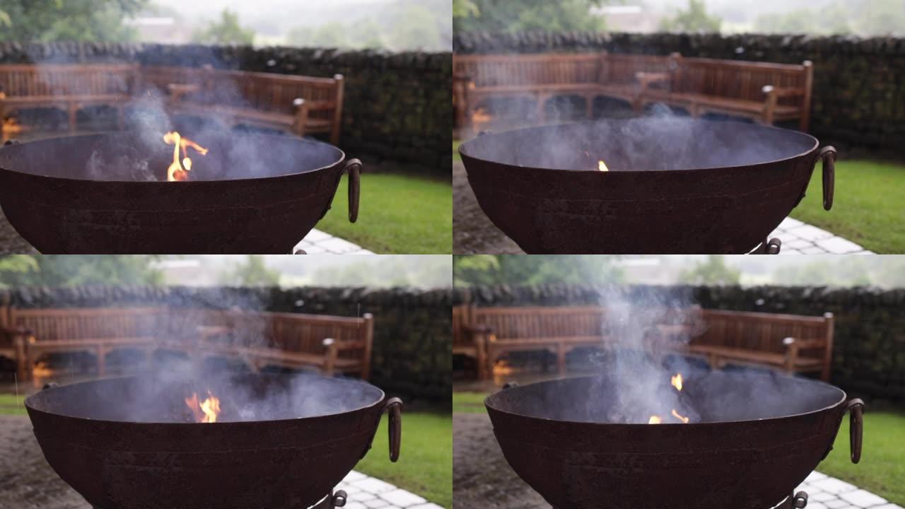 在雨天，火焰和烟雾以慢动作从火坑中升起