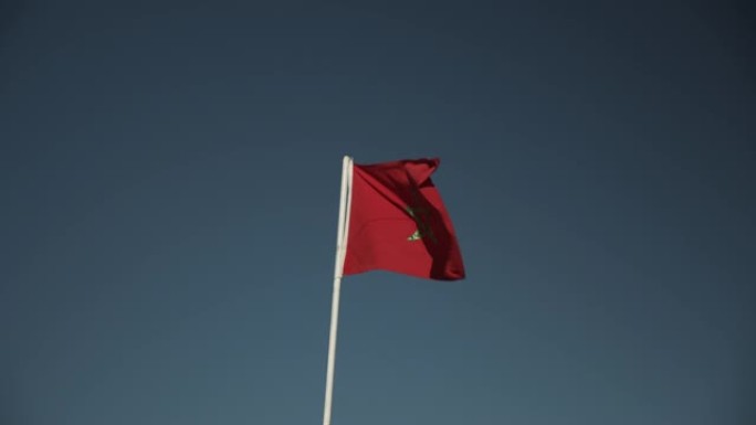 旗杆上随风飘扬的国旗。绿色交错的五角红旗。对抗晴朗天空的国家符号。摩洛哥、非洲