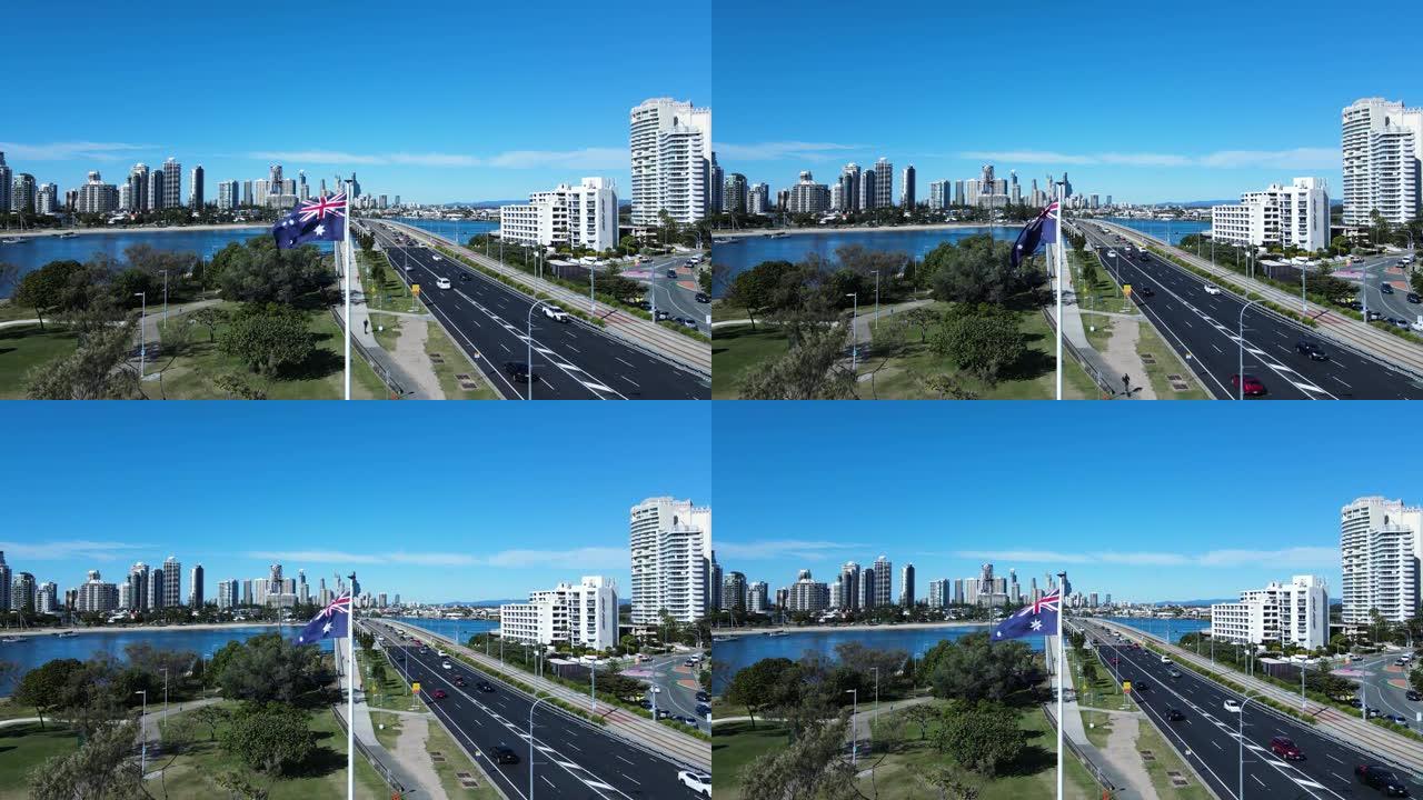 澳大利亚国旗在微风中挥舞着，毗邻繁忙的道路网络，通向高耸的城市天际线。无人机全景视图。