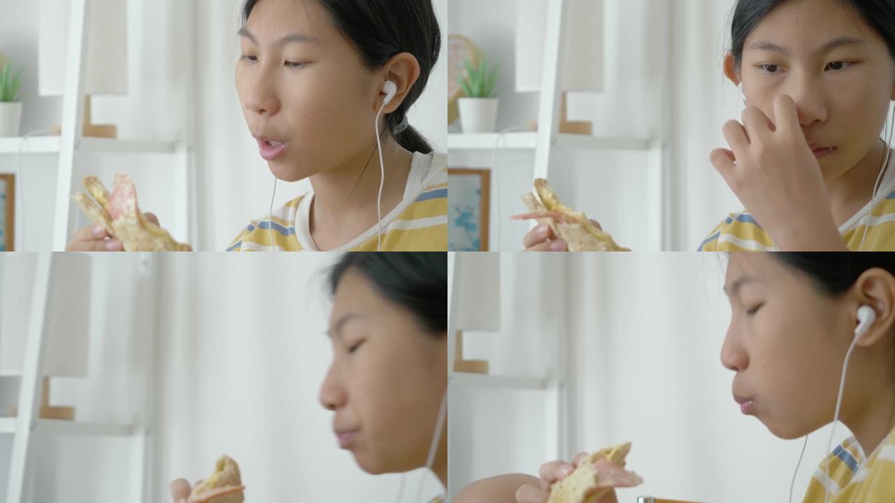亚洲女孩吃火腿烤面包，并在看智能手机电影时，生活方式概念。