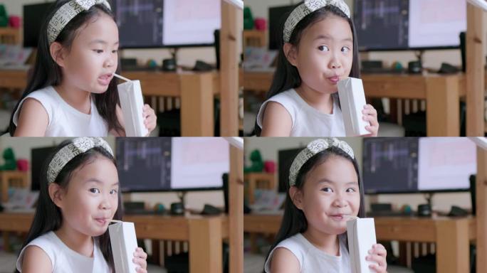 一个年轻的女孩高兴地喝了一盒白色的牛奶。