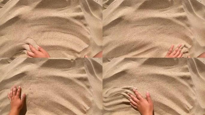 人将手放在黄沙表面，用手指将其散射。