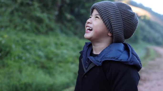 亚洲男孩戴着毛线帽，在冬季大笑