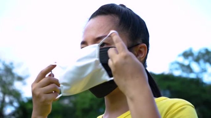 亚洲年轻女子佩戴两层医用防护口罩或双层口罩的肖像展示如何，对抗新型冠状病毒肺炎病毒爆发，医疗保健，流