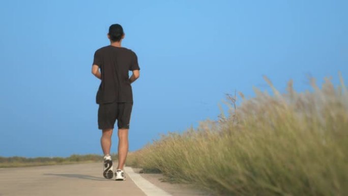 亚洲男子在公路上跑步冲刺。在户外锻炼和锻炼中适合男性健身运动员