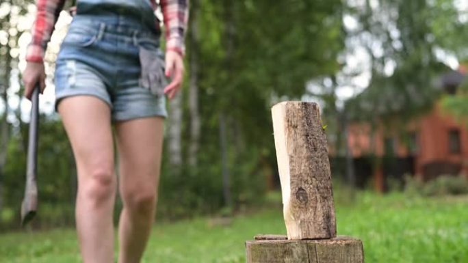 一个年轻的女人用斧头劈开一根木头