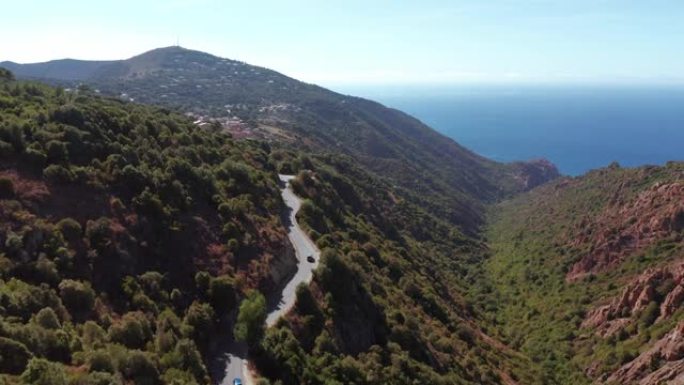 山谷鸟瞰图和夏季自然景观。红岩和电动车行驶的过山路，蓝海在背景中