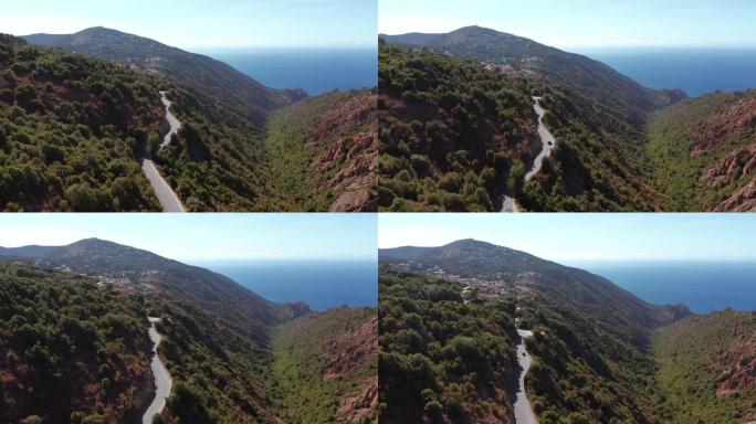 山谷鸟瞰图和夏季自然景观。红岩和电动车行驶的过山路，蓝海在背景中