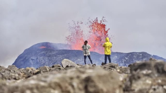 旅行者俯瞰喷发火山景观的壁纸视图