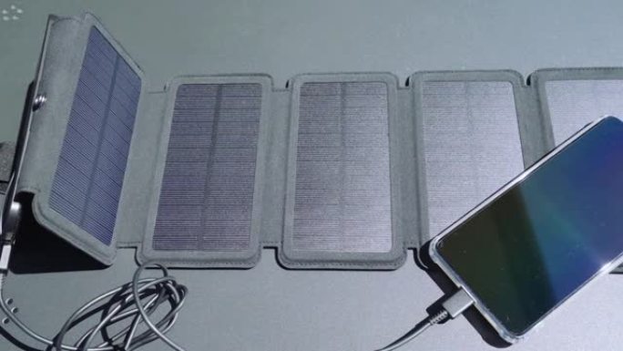 用便携式太阳能电池板充电器从家里给智能手机充电。使用小型太阳能电池板自我消费和充电i