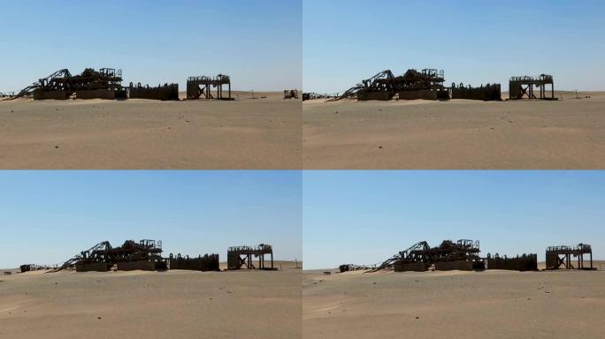 躺在沙漠沙子里的大锈蚀石油钻井平台