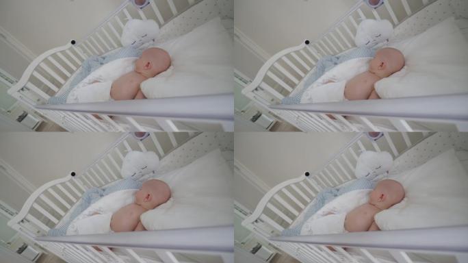 男婴睡在婴儿床里，婴儿床安装了IP无线安全摄像头作为婴儿监视器，内部是现代公寓卧室。