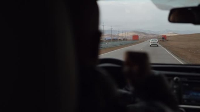 白天汽车在高速公路上行驶。第一人称视角从后座拍摄。山的前景。旅游之旅，旅游