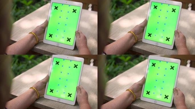 高级女性使用绿屏数字平板电脑，色度键