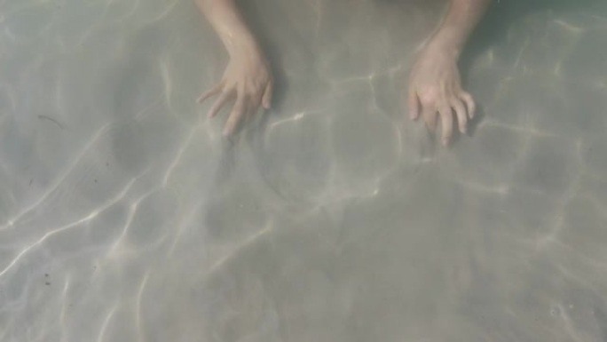 女人用手在沙子里水下画画