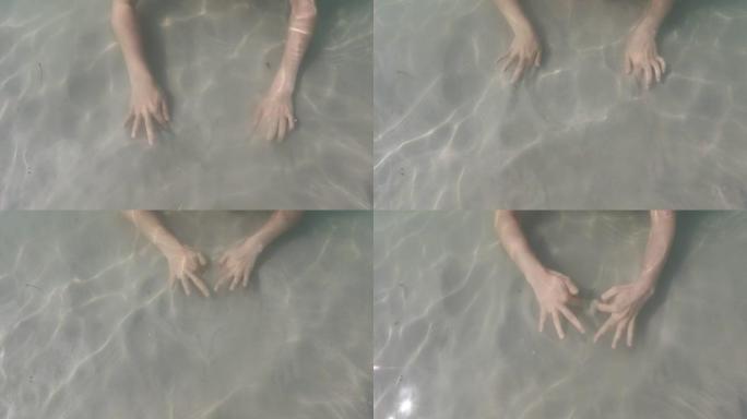 女人用手在沙子里水下画画