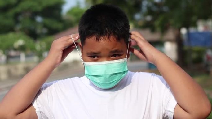 亚洲男孩在自然公园喂鱼并戴口罩防止冠状病毒爆发