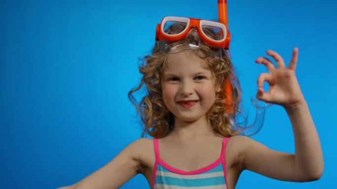 戴着游泳面具和通气管的小卷发女孩正在展示两个好的手势