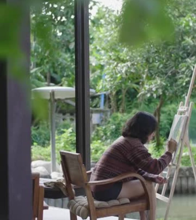 年轻的亚洲女性艺术家用画笔和画架绘画。