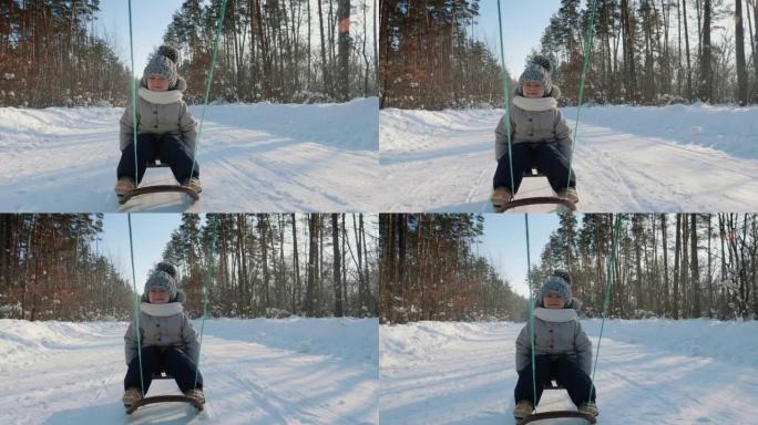 这个男孩在雪道上的雪橇上开车