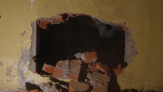 一名工人用手提钻在砖墙上打一个洞