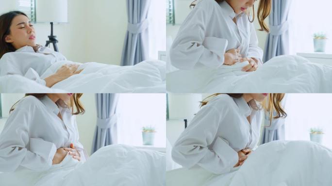 穿着睡衣的亚洲美丽生病的女孩在卧室睡觉。迷人的年轻女子在床上醒来后感到难受和疼痛，胃痛或月经，然后早