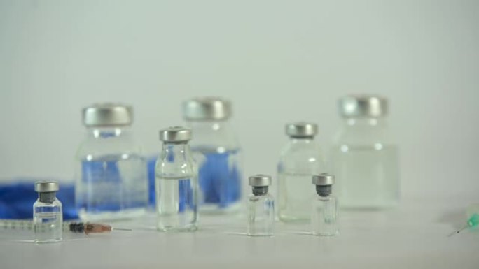 用于COVID-19和其他疫苗的玻璃瓶，配有不同大小的注射器和带摄像头的蓝色乳胶手套