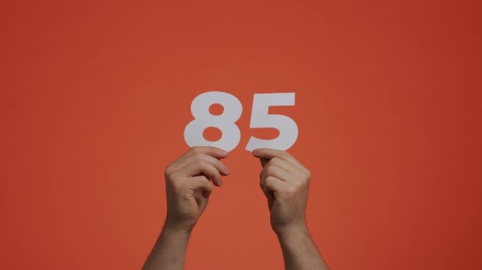 八十五号在手。显示数字的人，85个由雕刻纸制成的数字，用于投票，数学学习或销售