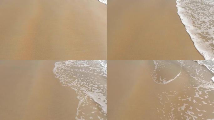 黄色细沙和白色泡沫海水在岸上吹来的镜头。光滑的白色海水泡沫形成固化图案。自然背景纹理。