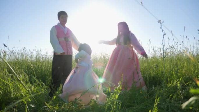 日落时，带着女儿的韩国家庭在草地上跳舞