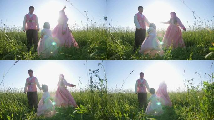 日落时，带着女儿的韩国家庭在草地上跳舞