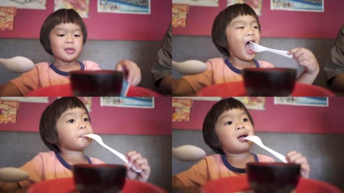 特写幼儿男孩在一家日本餐馆独自吃饭。