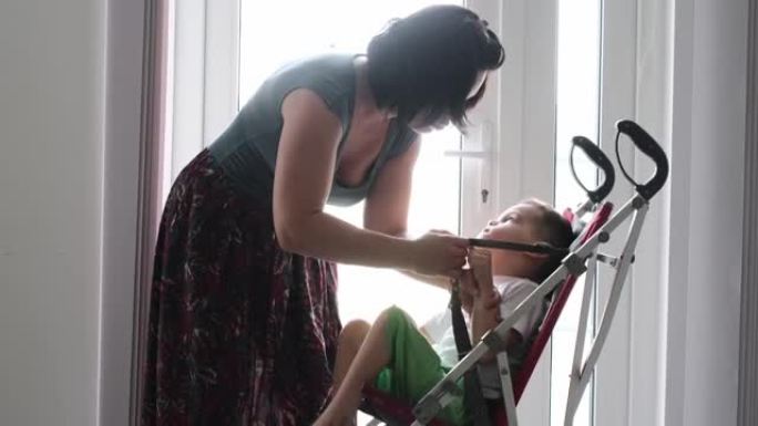 母亲将残疾儿童脑瘫放在轮椅上