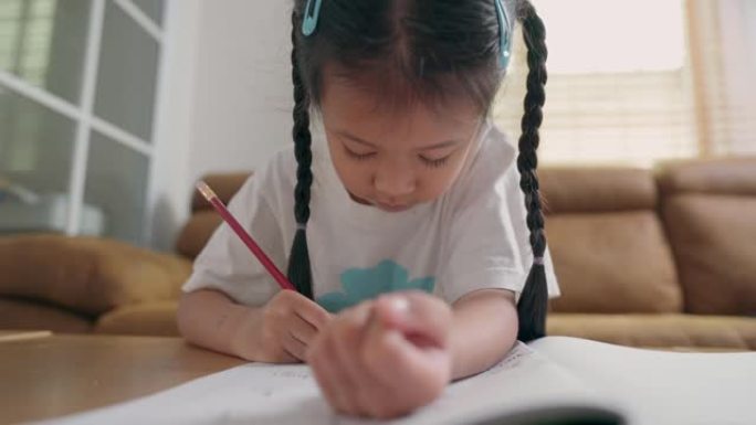 亚洲小女孩在家学习学校练习册上的写作