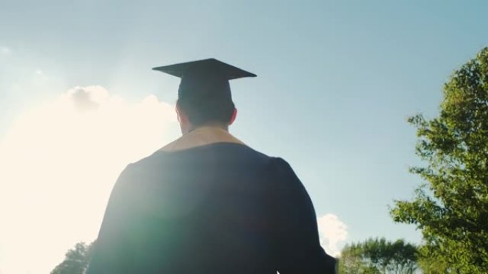 剪影日落时，大学毕业生的近距离后视图上路。慢动作镜头