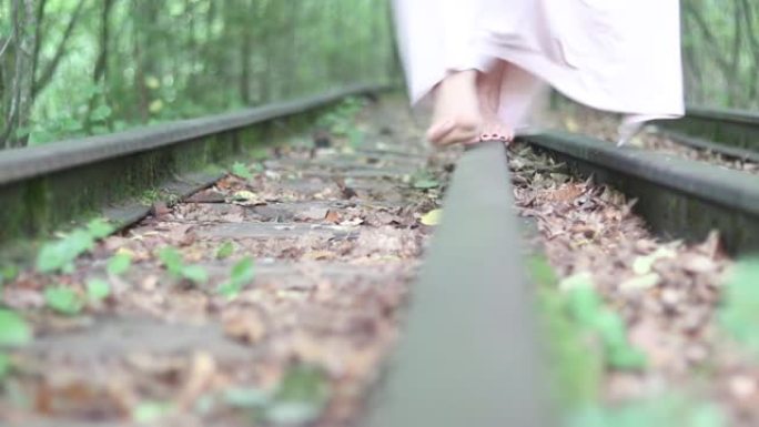 一个年轻女孩赤脚走在铁路上。