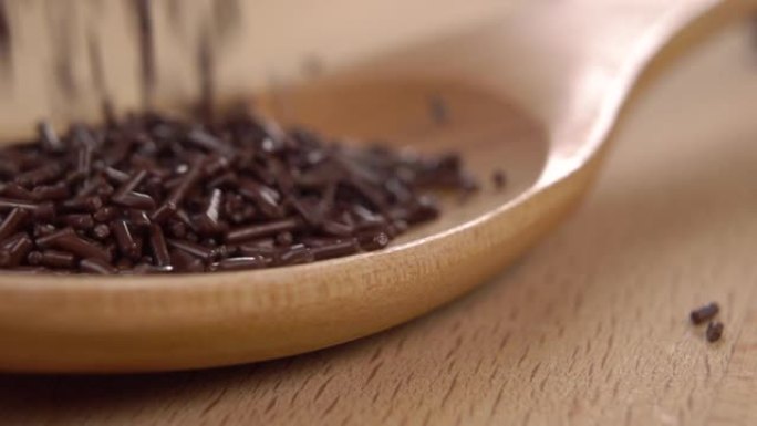 黑巧克力洒落在木勺上，散落在木材表面