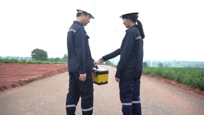 两名身穿制服的亚洲工程师在win涡轮机农场工作。