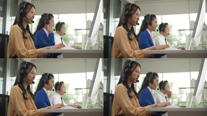 亚洲女性呼叫中心代理在其工作站上与客户交谈