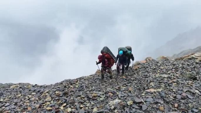 四个背着大背包的游客在雨中沿着手推车行走