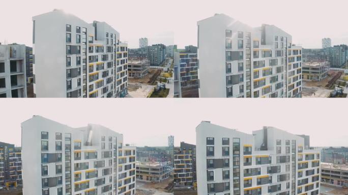 建筑工地，建筑工作流程现代化镇街上的公寓楼。未完成的结构城市公寓楼。带窗户、斜屋顶和道路的立面鸟瞰图