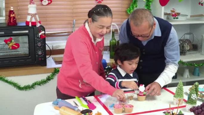 孙子，少年男孩快乐学习准备，模具
给圣诞老人和祖父、祖母结冰。东南亚多代家庭的概念，一个孩子在厨房里